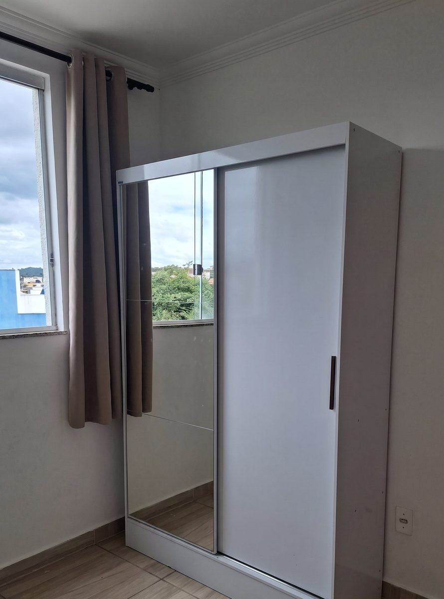 Guarda-roupa branco com porta de correr e espelho montado em quarto